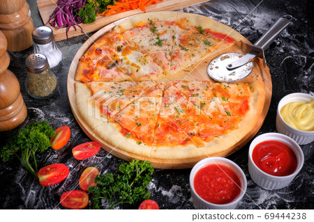 Salmon Seafood Pizza on a Black table with ingredients around Salmon Seafood Pizza on a Black table with ingredients around 69444238