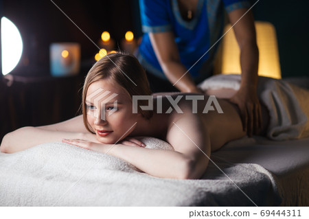Hands massaging the back, lying on the belly of a woman Hands massaging the back, lying on the belly of a woman 69444311