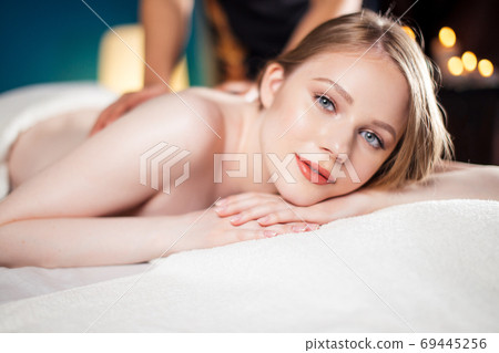 Beautiful, young and healthy woman is having hot stone massage. Spa Treatment 69445256