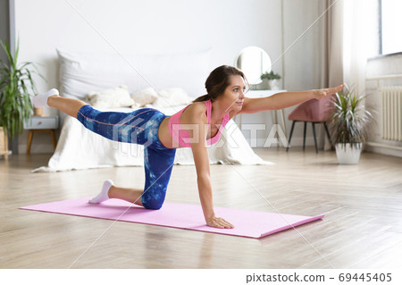 Woman working out at home on exercise mat. Horizontal photo. 69445405
