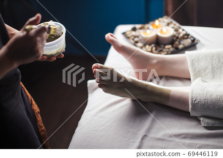 Procedure of applying clay mask on foot by beautician. Mud therapy. 69446119