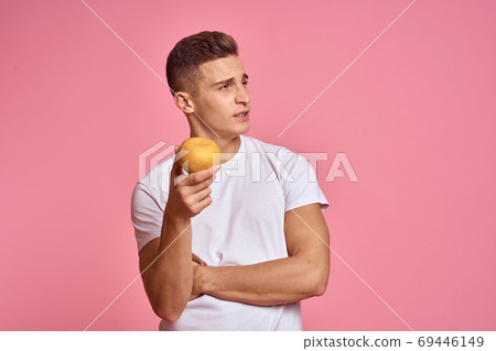 Man with fruits in hands on a pink background healthy food vitamins pink background white t-shirt model Man with fruits in hands on a pink background healthy food vitamins pink background white t-shirt model 69446149