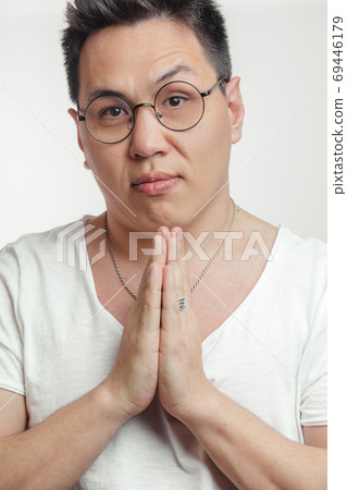 Asian man in t-shirt, holding hands in pray, begging for help or asking apology 69446179
