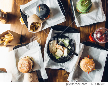 Burgers with vegetables and fries on a wooden board, top view. Burgers with vegetables and fries on a wooden board, top view. 69446306