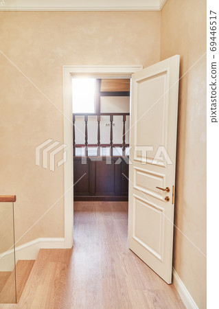 Opened white door to the home library with wooden balustrade. Classic style white door 69446517