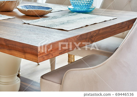 Wooden dinner table on massive legs with dishware in modern apartment. Close-up 69446536
