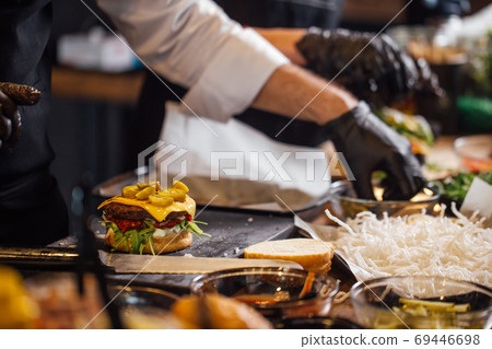 The chef prepares a Burger with beef, salad and vegetables. The chef prepares a Burger with beef, salad and vegetables. 69446698