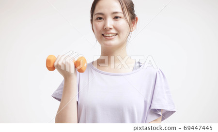 Young woman doing muscle training with dumbbells 69447445