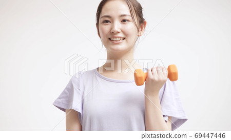 Young woman doing muscle training with dumbbells 69447446