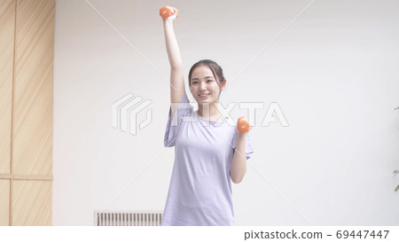 Young woman doing muscle training with dumbbells 69447447