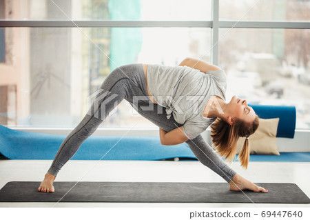 woman practicing yoga , Triangle pose in fitness center woman practicing yoga , Triangle pose in fitness center 69447640