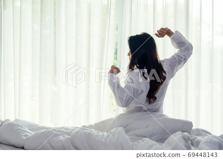 Asian women waking up stretching and raise arms in bed room at home Asian women waking up stretching and raise arms in bed room at home 69448143