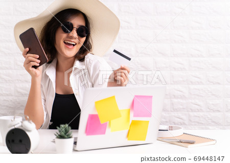 Happy woman wearing hat and sunglasses use smart phone and credi 69448147