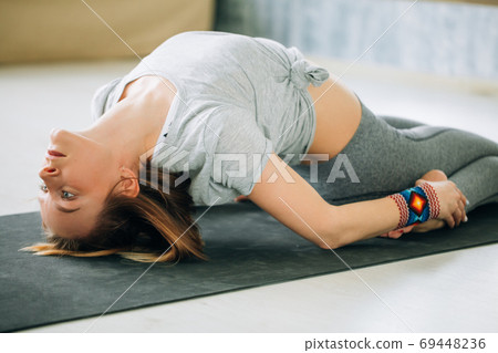 adult woman in supta virasana yoga position in studio 69448236