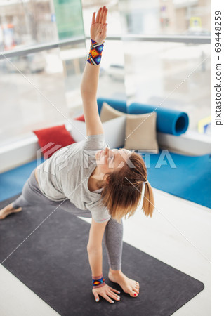 woman practicing yoga , Triangle pose in fitness center woman practicing yoga , Triangle pose in fitness center 69448259