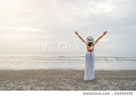 freedom woman in bikini walking with arms raised on sea beach 69448498