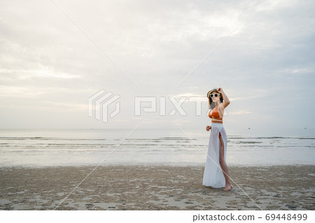 cheerful woman in bikini standing at sea beach 69448499