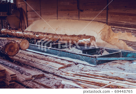 Sawmill. Process of machining logs in sawmill machine saws the tree trunk Sawmill. Process of machining logs in sawmill machine saws the tree trunk 69448765