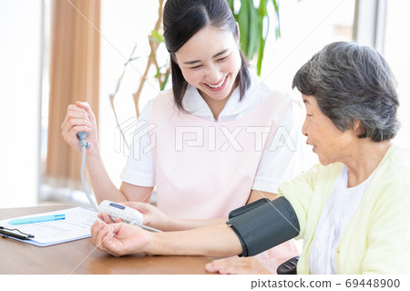 高級婦女和護理人員測量血壓的護理人員 69448900