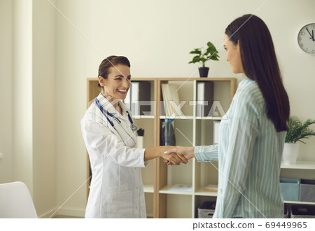 Smiling woman doctor shaking hand to woman patient after consultation in medical clinic office Smiling woman doctor shaking hand to woman patient after consultation in medical clinic office 69449965