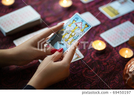 Tarot reader picking tarot cards near burning candles. Tarot reader picking tarot cards near burning candles. 69450197