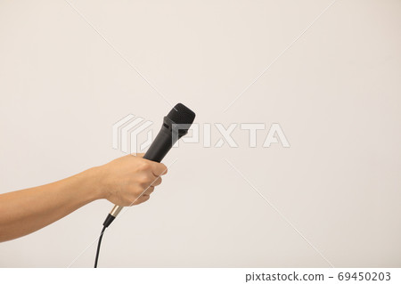 A man's hand holding a microphone in an interview, etc. 69450203