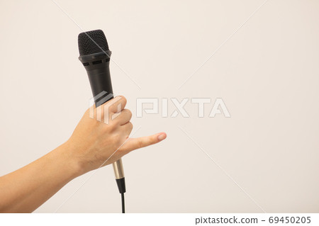 A man's hand holding a microphone (pinky finger standing up!) Photo material 69450205