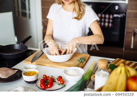 Home cozy kitchen chef pours salt on pork or beef meat with salt shaker Barbecue concept or healthy meat lifestyle shot 69450320