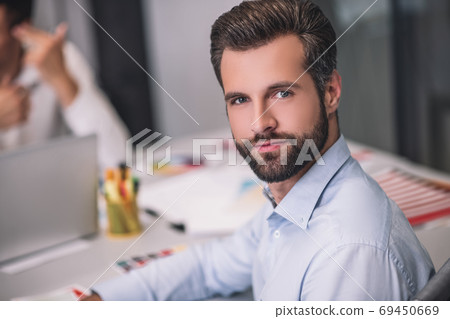 Bearded male sitting at table, looking into camera Bearded male sitting at table, looking into camera 69450669