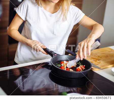 Cropped view of young happy housewife frying chicken meat for dinner Cropped view of young happy housewife frying chicken meat for dinner 69450671