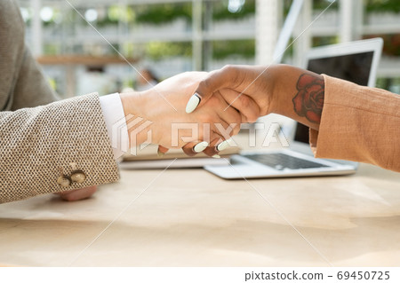 Handshake of young intercultural business partners over table after making deal 69450725