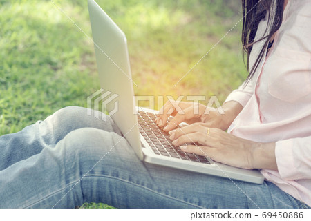 Asian woman sitting green park using laptop computer. Woman working on laptop Asian woman sitting green park using laptop computer. Woman working on laptop 69450886