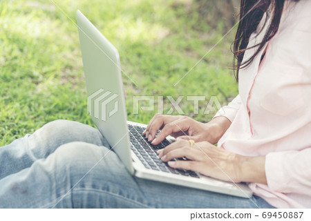 Asian woman sitting green park using laptop computer. Woman working on laptop Asian woman sitting green park using laptop computer. Woman working on laptop 69450887