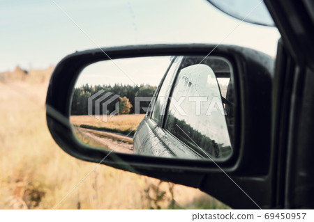 Reflection of dirty car and landscape in left rearview mirror on sunny summer day Reflection of dirty car and landscape in left rearview mirror on sunny summer day 69450957