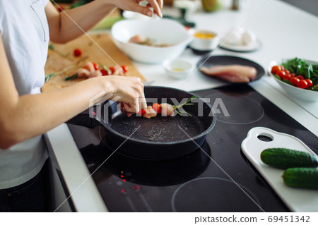 Closeup of woman roasting kebabs on frying pan Closeup of woman roasting kebabs on frying pan 69451342