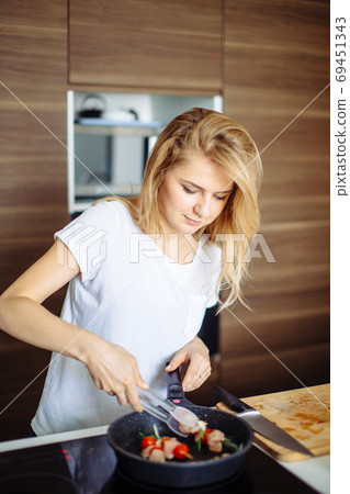 Closeup of woman roasting kebabs on frying pan Closeup of woman roasting kebabs on frying pan 69451343