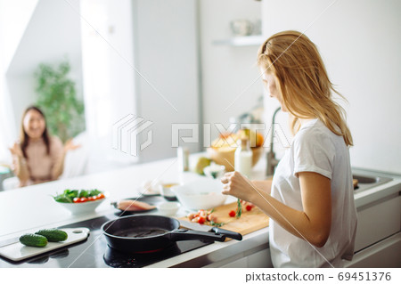 Young housewife making meal for linch in kitchen. rear view Young housewife making meal for linch in kitchen. rear view 69451376