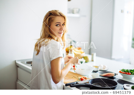 Young housewife making meal for linch in kitchen. rear view Young housewife making meal for linch in kitchen. rear view 69451379