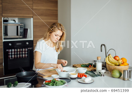 Pleasant young woman preparing dinner in a kitchen concept cooking, culinary 69451399