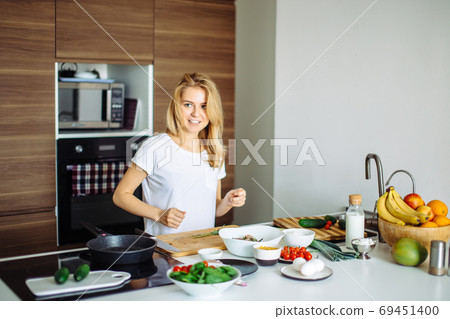 Pleasant young woman preparing dinner in a kitchen concept cooking, culinary Pleasant young woman preparing dinner in a kitchen concept cooking, culinary 69451400
