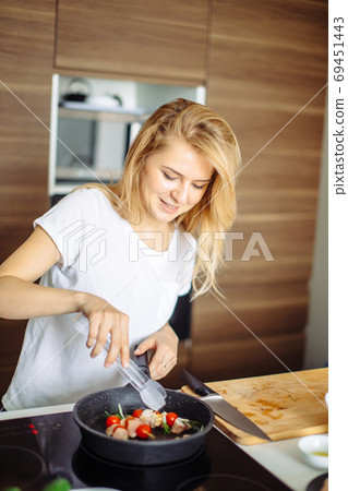 Closeup of woman roasting kebabs on frying pan Closeup of woman roasting kebabs on frying pan 69451443