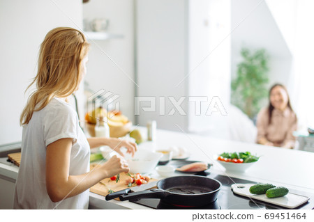 Young housewife making meal for linch in kitchen. rear view Young housewife making meal for linch in kitchen. rear view 69451464