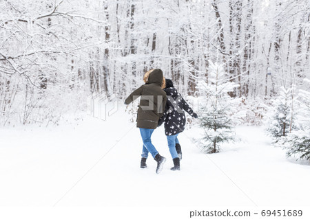 Happy couple walking through a snowy forest in winter Happy couple walking through a snowy forest in winter 69451689