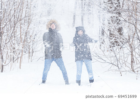 Love, relationship, season and friendship concept - man and woman having fun and playing with snow in winter forest Love, relationship, season and friendship concept - man and woman having fun and playing with snow in winter forest 69451699