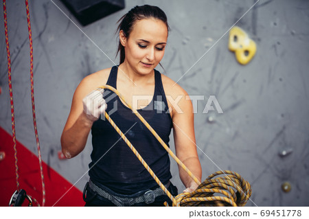 Climber girl in safety harness tying rope in eight knot and preparing to climb, view of hands 69451778