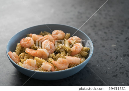 Fusilli with shrimps and pesto in a blue bowl on concrete background Fusilli with shrimps and pesto in a blue bowl on concrete background 69451881
