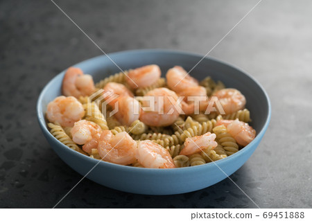 Fusilli with shrimps and pesto in a blue bowl on concrete background Fusilli with shrimps and pesto in a blue bowl on concrete background 69451888