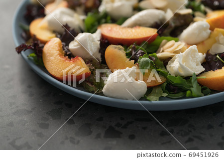 salad with nectarines, mozzarella and mixed greens in blue plate on concrete background salad with nectarines, mozzarella and mixed greens in blue plate on concrete background 69451926