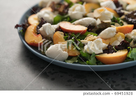 salad with nectarines, mozzarella and mixed greens in blue plate on concrete background salad with nectarines, mozzarella and mixed greens in blue plate on concrete background 69451928