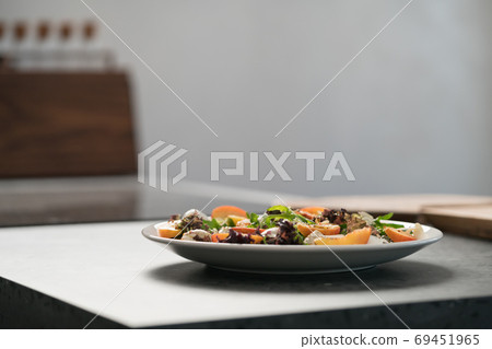 Closeup salad with nectarines, mozzarella and mixed greens in white plate on concrete countertop 69451965